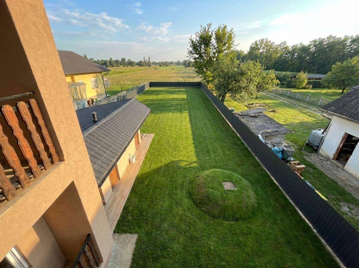 Weitläufiger Gartenbereich mit gepflegtem Rasen und Blick auf die umliegende Landschaft und Felder.