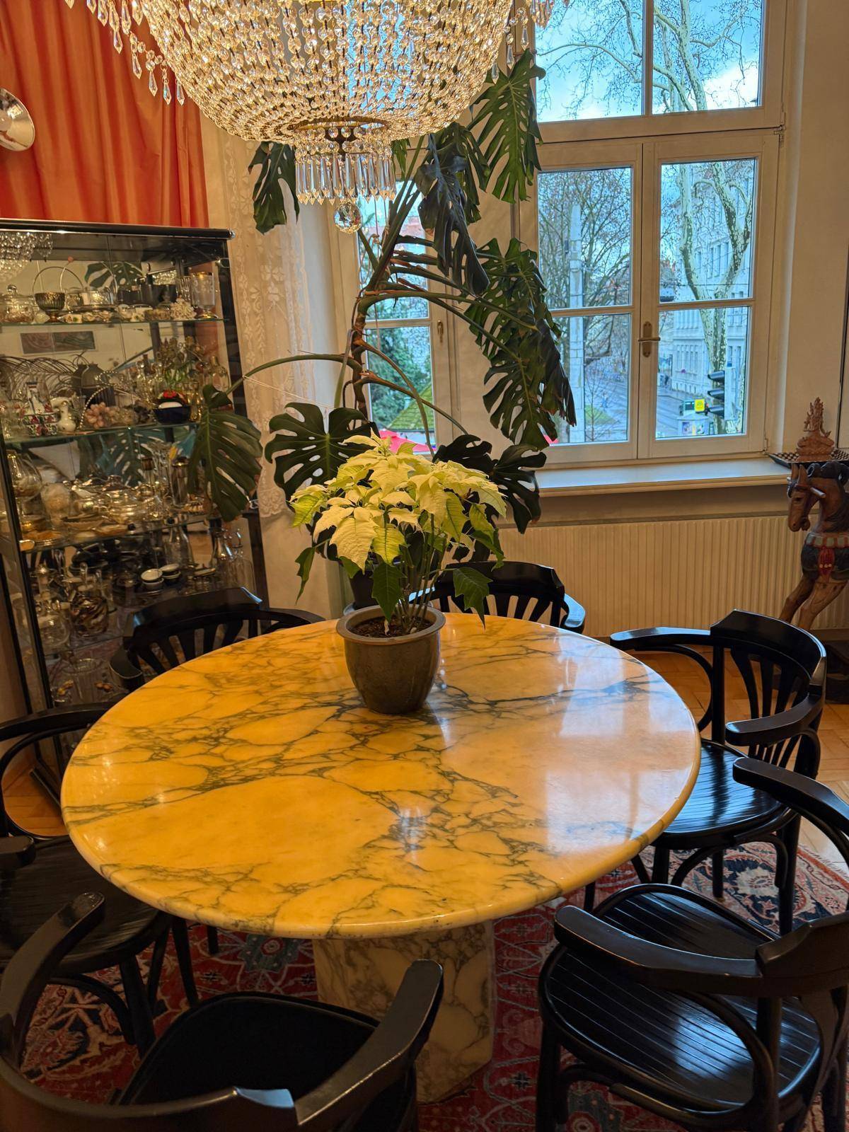 Eleganter Essbereich mit Marmortisch, Kronleuchter und Blick auf die Straße.