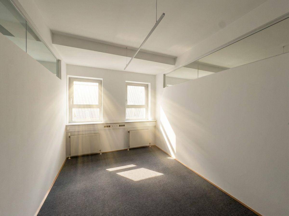 Kleinerer Büroraum mit zwei Fenstern, die für ausreichend Helligkeit und Belüftung sorgen.