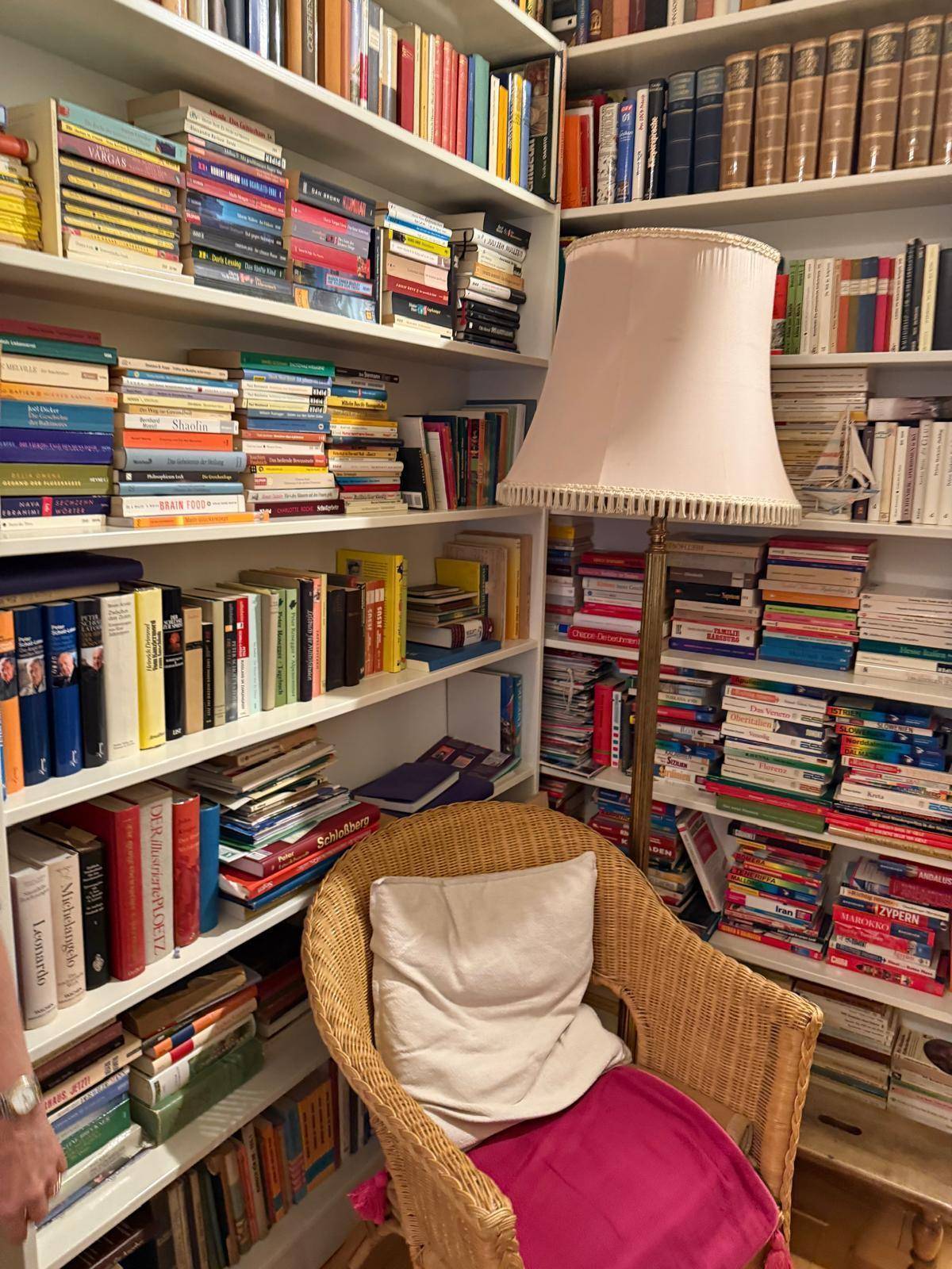 Gemütliches Arbeitszimmer mit raumhohen Bücherregalen und einem bequemen Sessel.