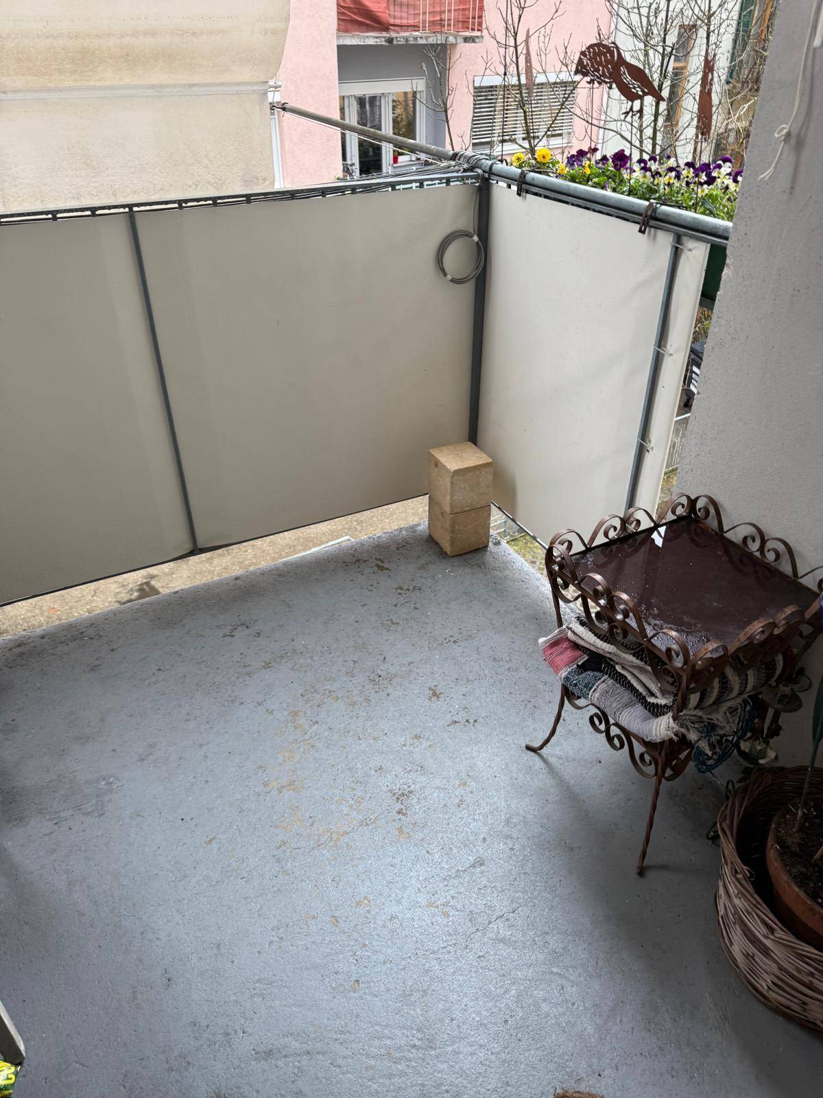 Kleiner Balkon mit Sichtschutz, einfacher Einrichtung und Blick auf die Umgebung.