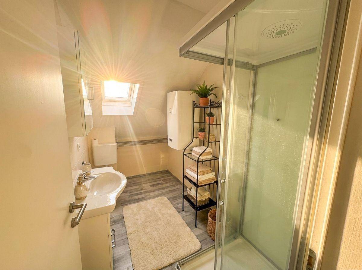 Modernes Badezimmer mit Dusche, Waschbecken und Dachfenster, das viel Licht spendet.
