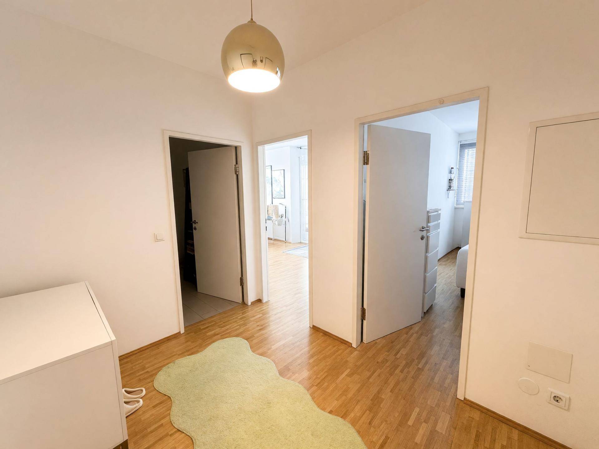 Heller Flur mit Holzboden und mehreren Türen, die zu den angrenzenden Zimmern führen.