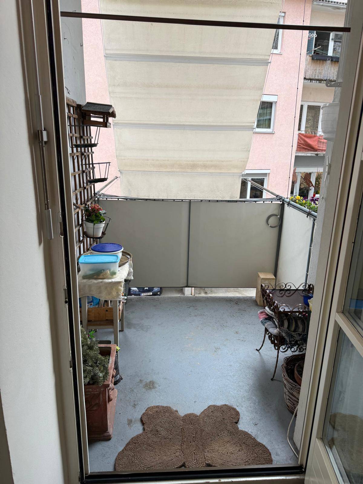 Balkon mit Markise, Sichtschutz und Blick auf die umliegenden Gebäude.