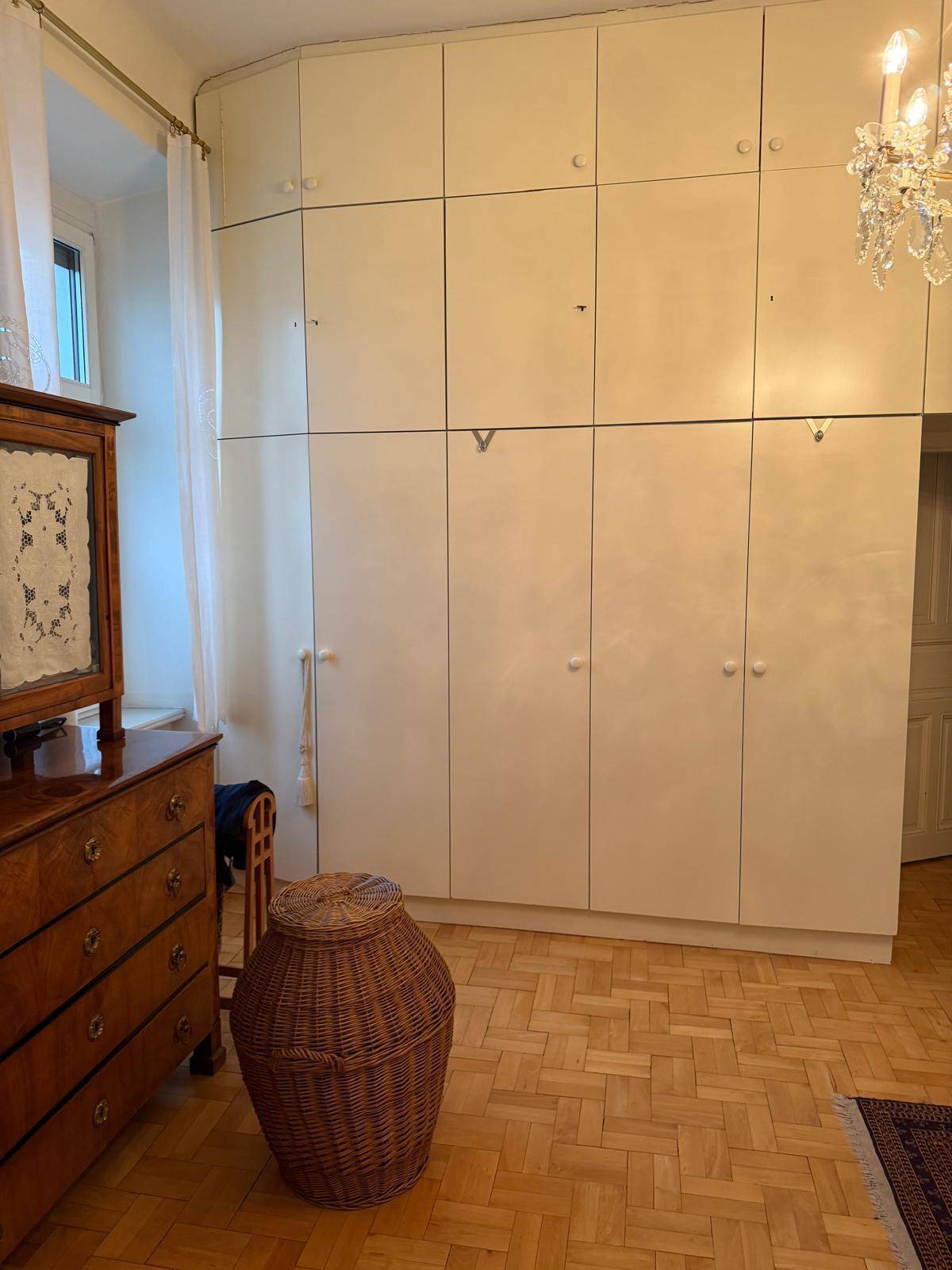 Schlafzimmer mit Einbauschränken, Parkettboden und einem Fenster für natürliches Licht.
