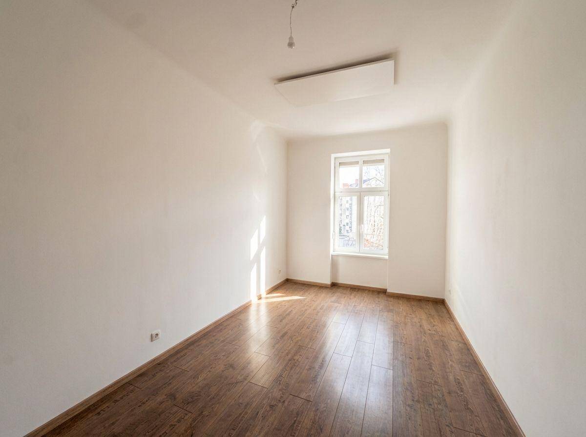 Gemütliches Zimmer mit Holzboden und einem Fenster, das viel Tageslicht hereinlässt.