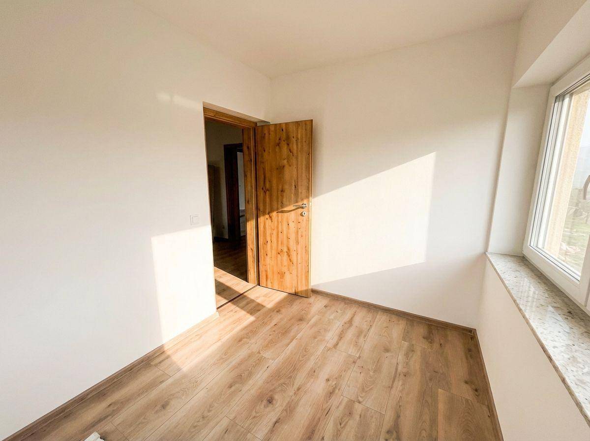 Leeres Zimmer mit Laminatboden, weiß gestrichenen Wänden und einem Fenster mit Granitfensterbank.