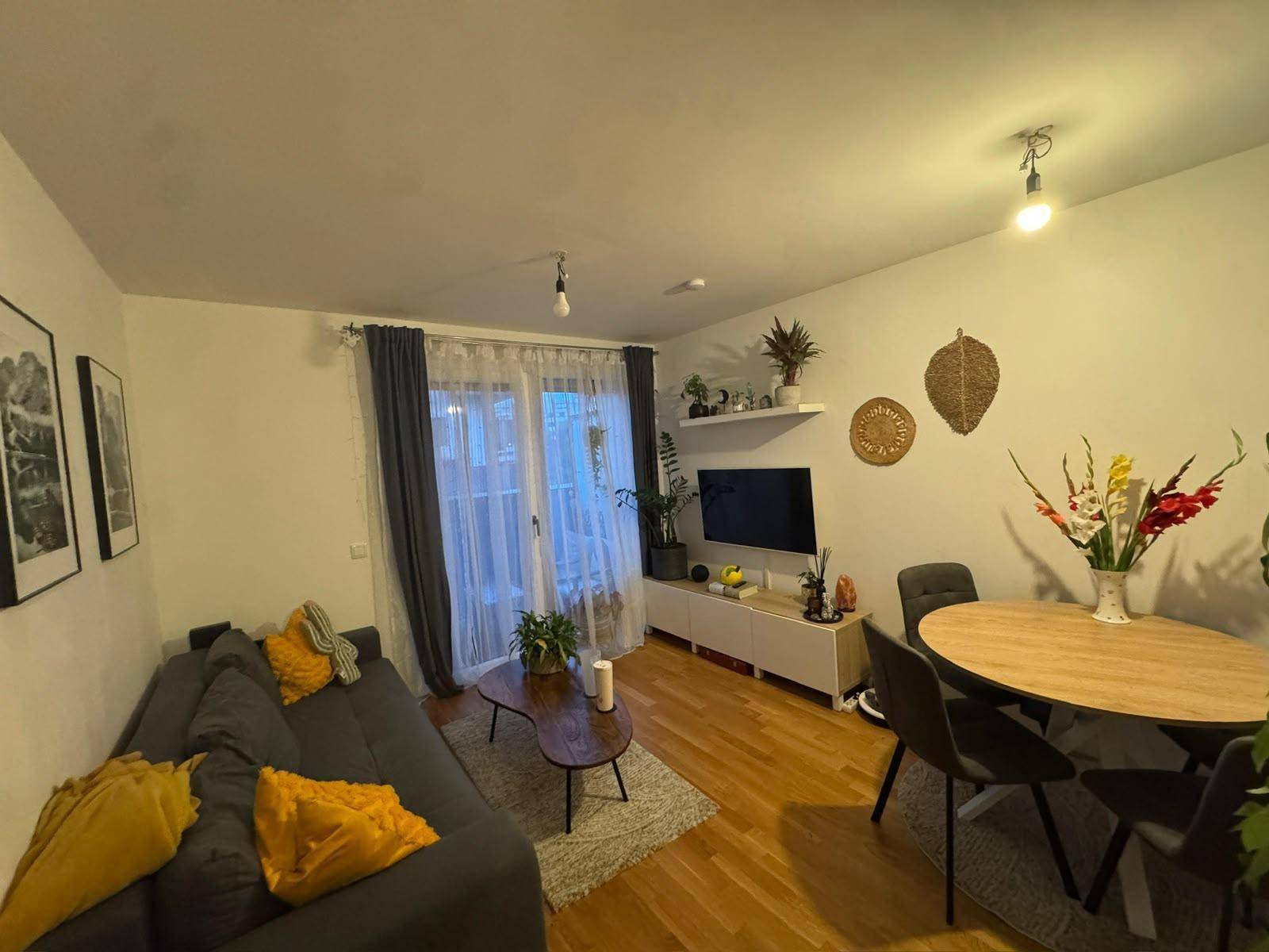 Heller Wohn-Essbereich mit Sofa, Esstisch und Balkonzugang.