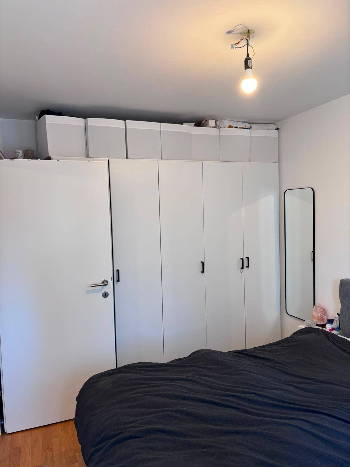Schlafzimmer mit großem Kleiderschrank, Doppelbett und Holzboden.