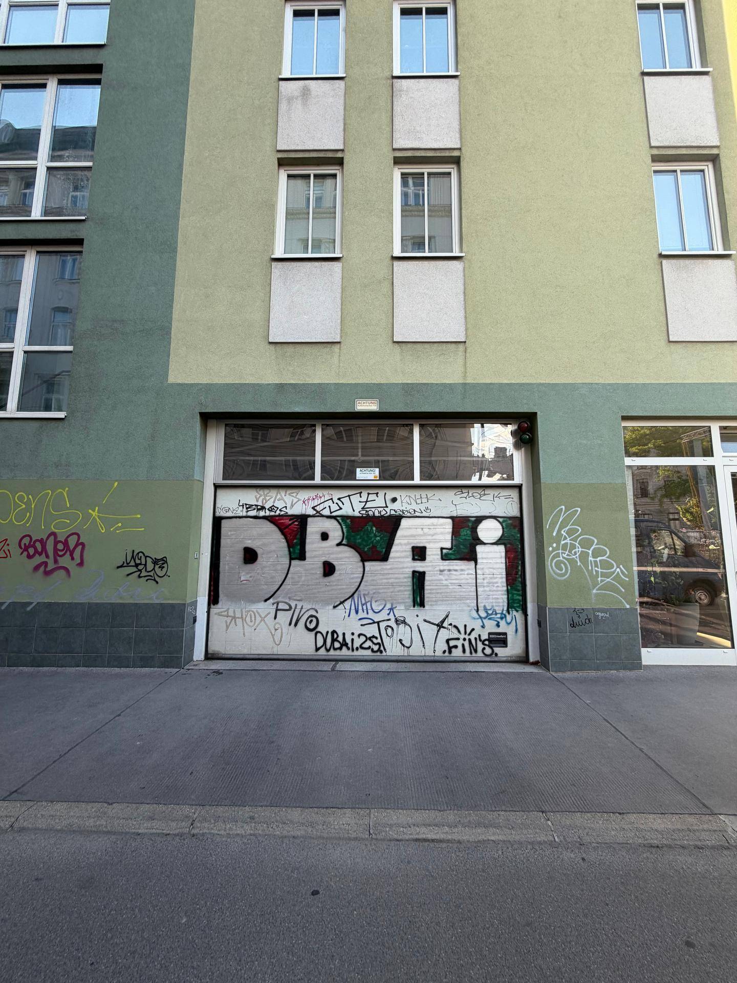 Die Fassade eines Gebäudes mit einem geschlossenen Garagentor, das mit Graffiti bedeckt ist.