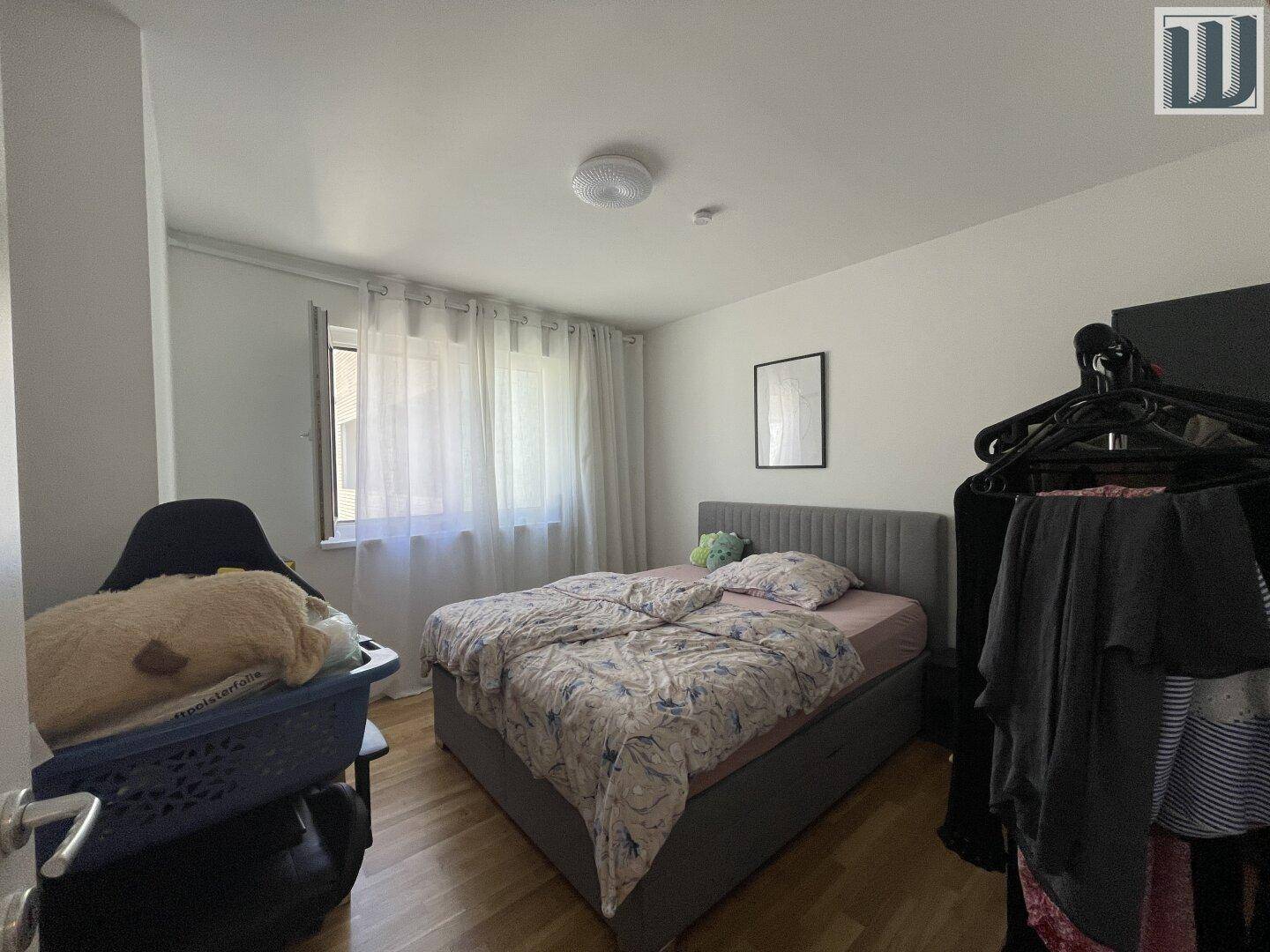 Gemütliches Schlafzimmer mit Doppelbett, Holzfußboden und Fenster mit Vorhängen.