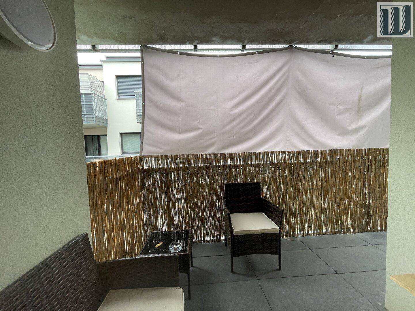 Gemütlicher Balkon mit Sitzgelegenheiten und Sichtschutz, ideal für entspannte Stunden im Freien.