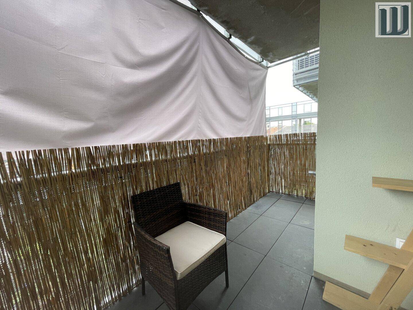 Balkon mit Rattan-Sessel und Bambus-Sichtschutz, bietet einen privaten Außenbereich.