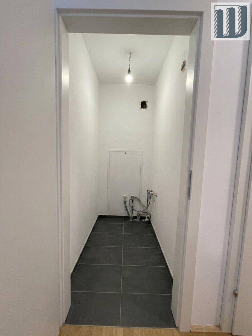 Schmaler Hauswirtschaftsraum mit Fliesenboden und Anschlüssen für Waschmaschine oder Trockner.