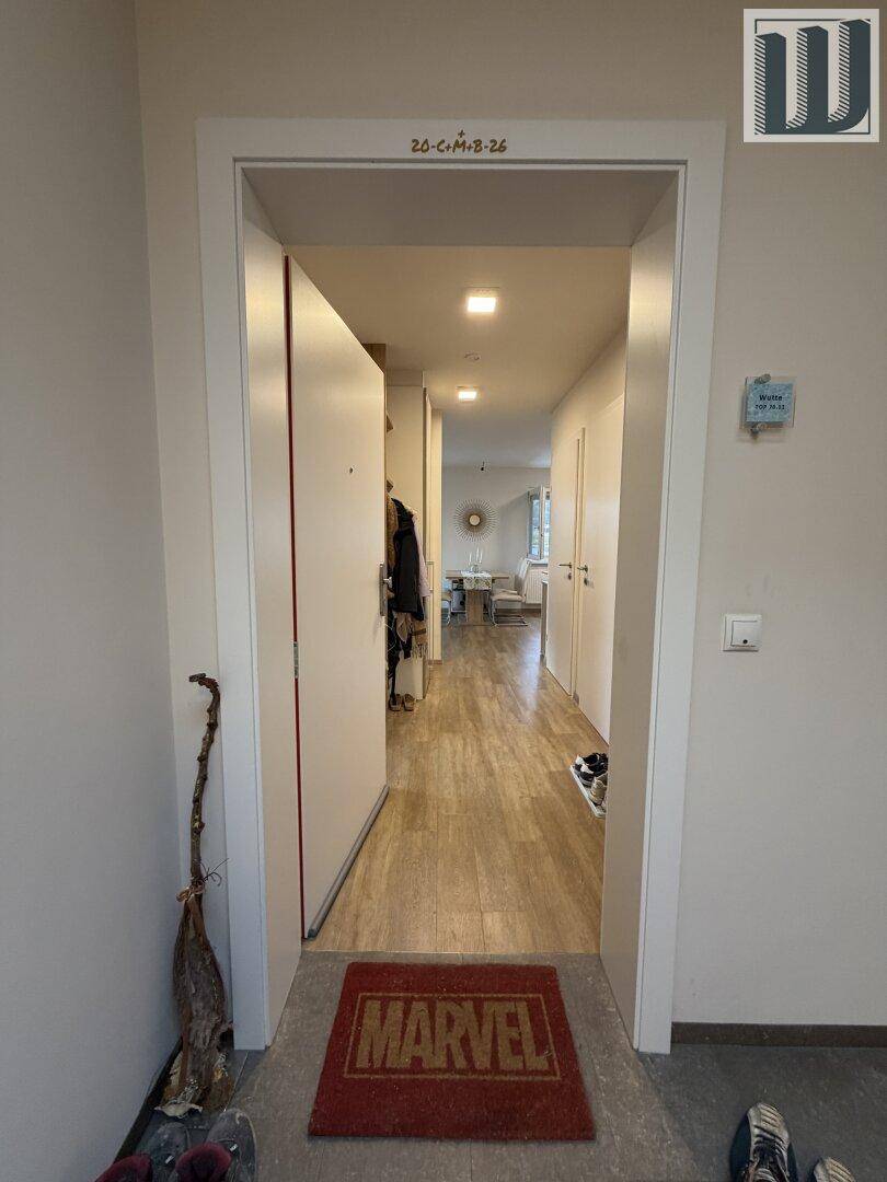 Heller Eingangsbereich mit Laminatboden, der zu den Wohnräumen führt.