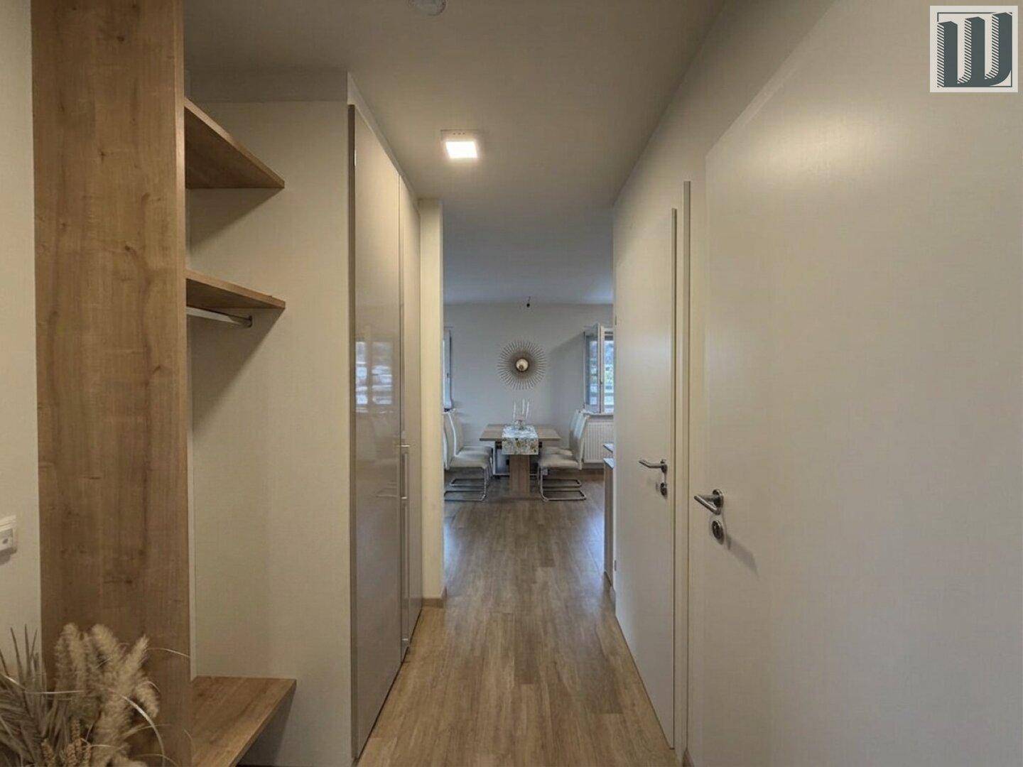 Moderner Flur mit integrierten Schränken und Holzregalen, der zum Essbereich führt.