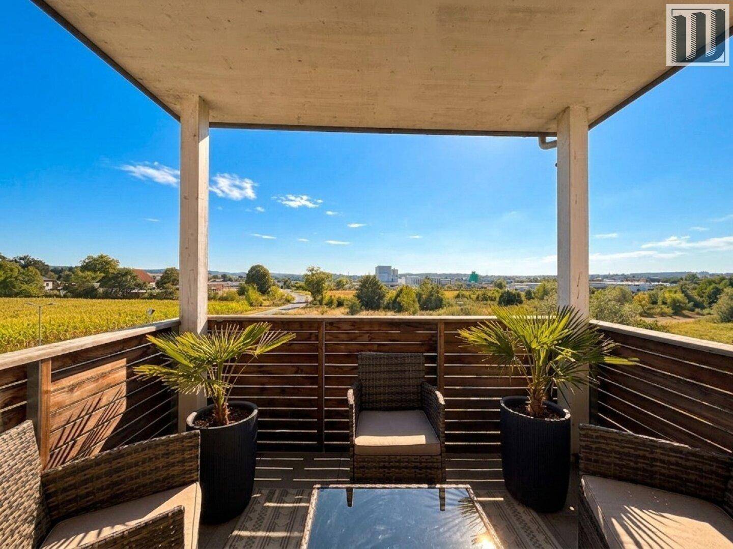 Geräumiger Balkon mit Sitzgelegenheiten und weitem Blick über die Landschaft und Stadt.