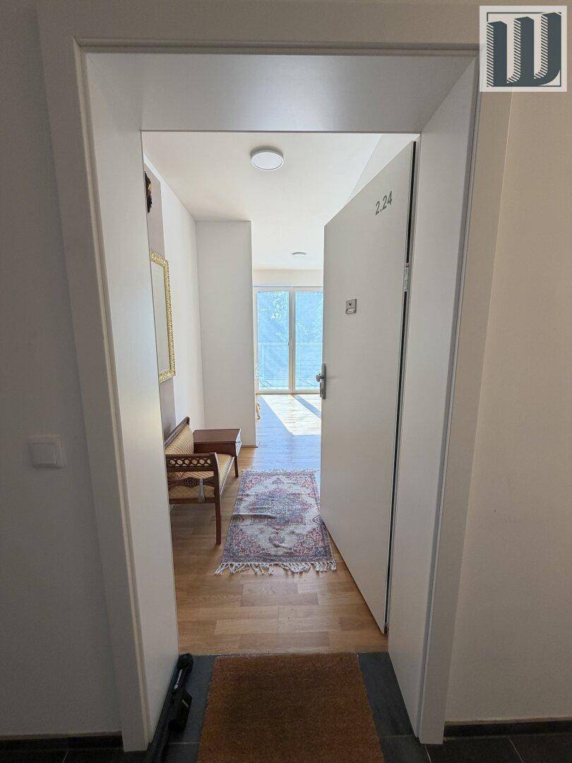 Heller Eingangsbereich einer Wohnung mit Holzboden und Blick in den Wohnbereich.