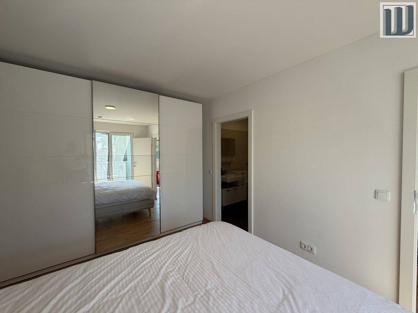 Schlafzimmer mit großem Spiegelschrank und Zugang zu einem weiteren Raum.