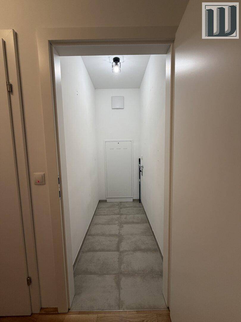 Schmaler Eingangsbereich oder Flur mit modernen grauen Fliesen und weiß gestrichenen Wänden.