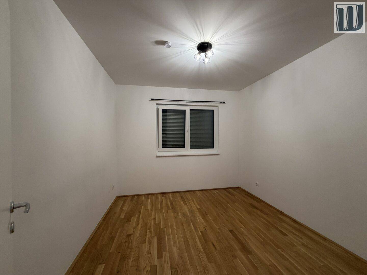 Helles Schlafzimmer mit Holzboden und Fenster, das eine angenehme Atmosphäre schafft.