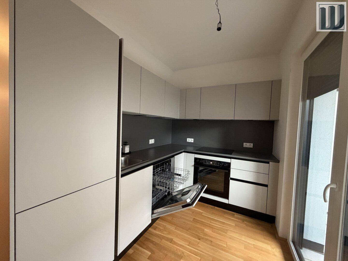 Moderne Küche mit grauen Schränken, dunklen Arbeitsplatten und integriertem Geschirrspüler.