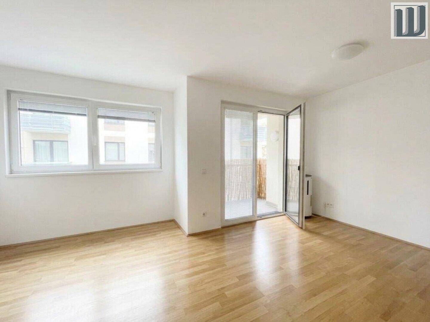 Helles Wohnzimmer mit Holzboden und Zugang zu einem Balkon, ideal für entspannte Stunden.