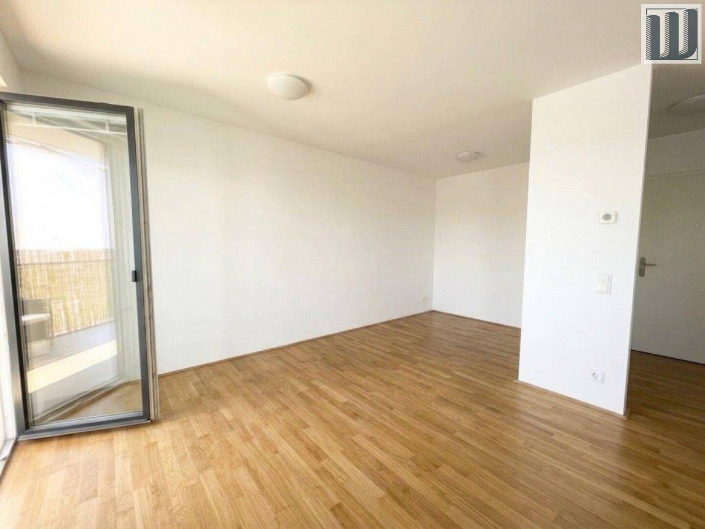 Geräumiges Wohnzimmer mit Holzboden und Balkonzugang, bietet viel Platz und Helligkeit.