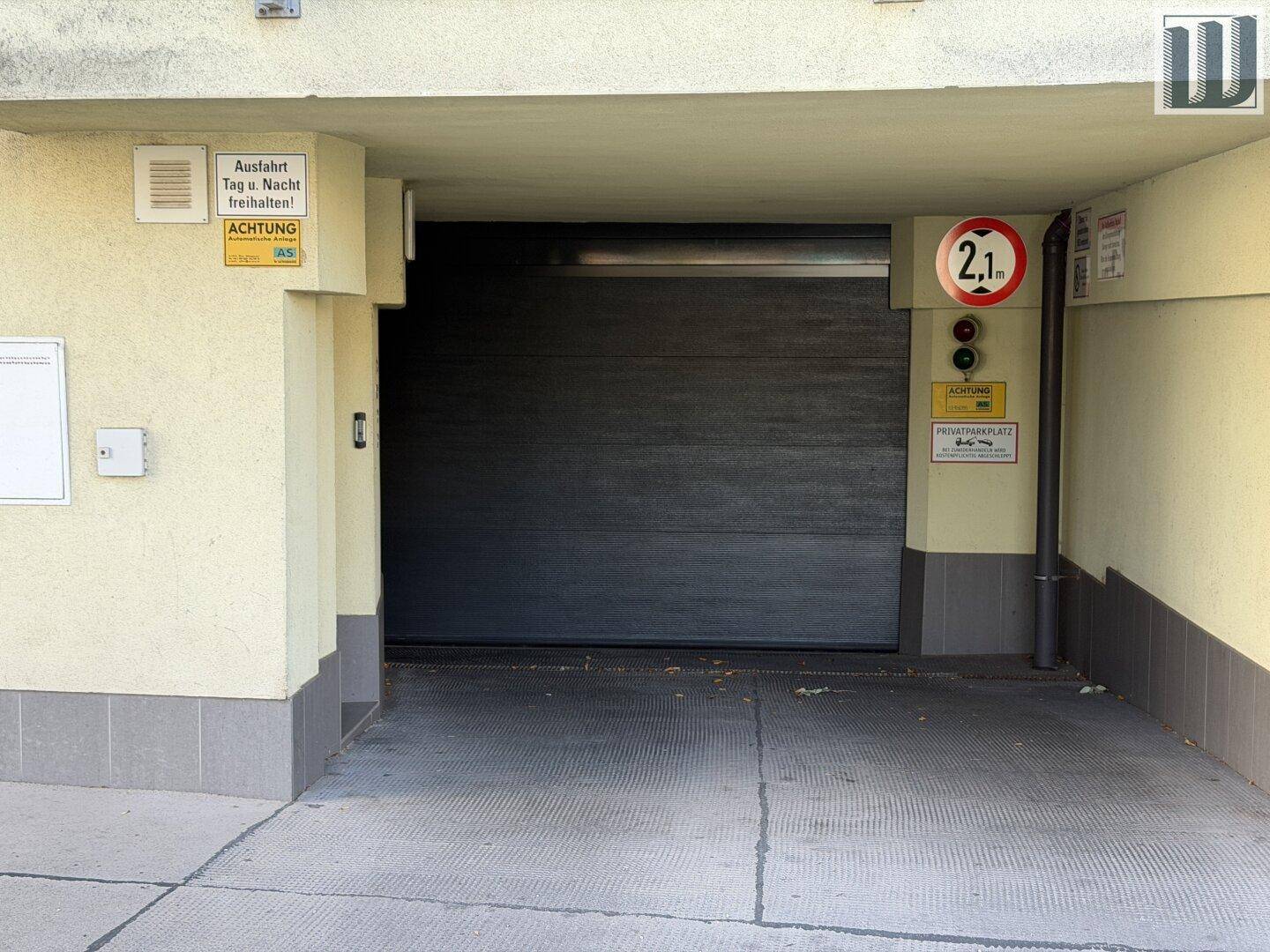 Einfahrt zur Tiefgarage mit geschlossenem Tor, Höhenbegrenzung und Warnhinweisen.