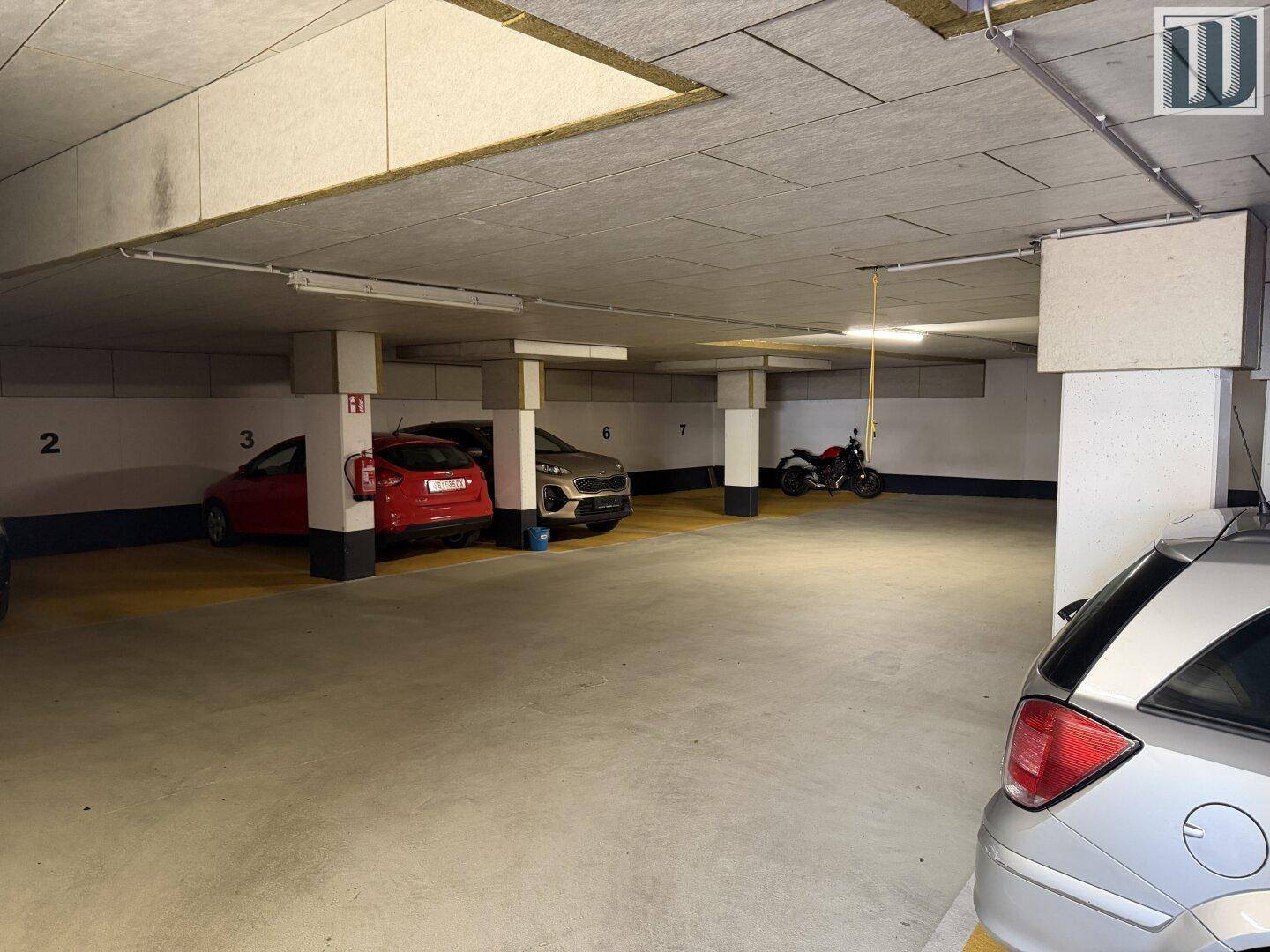 Geräumige Tiefgarage mit mehreren geparkten Fahrzeugen und klar markierten Stellplätzen.