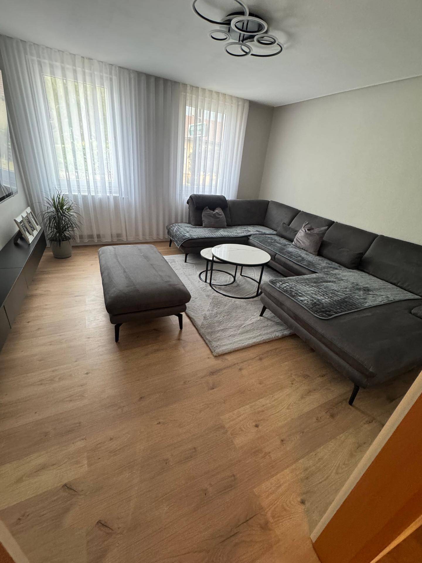 Helles Wohnzimmer mit großem Ecksofa, modernem Couchtisch und hellem Holzfußboden.