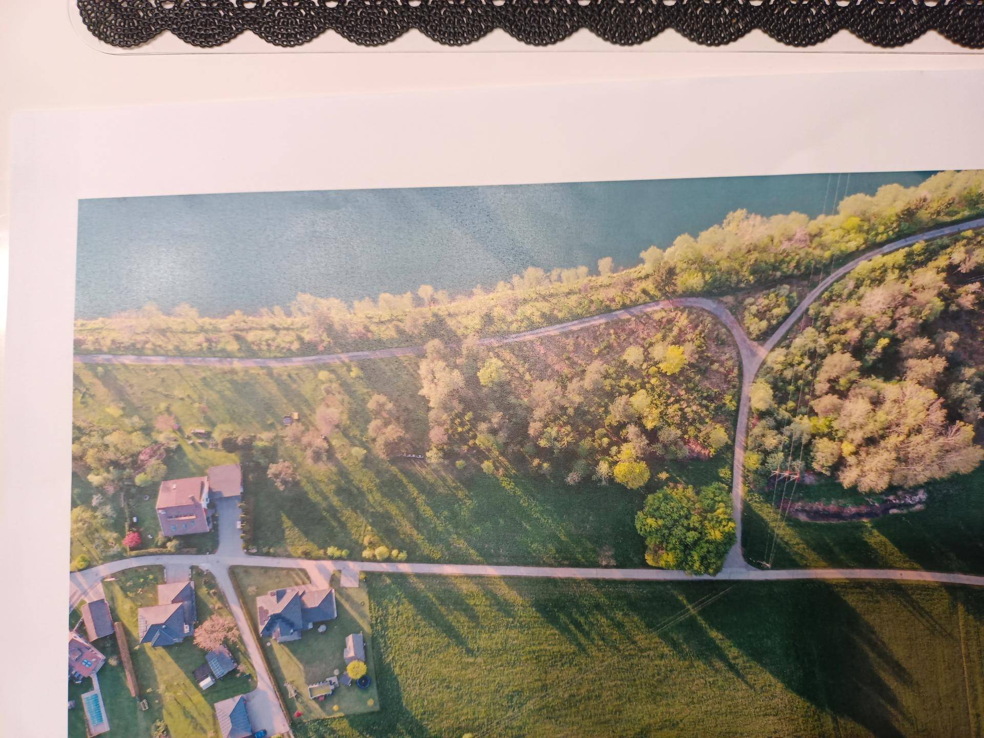 Panoramablick aus der Vogelperspektive auf eine ländliche Gegend mit Fluss, Wegen und Wohnbebauung.