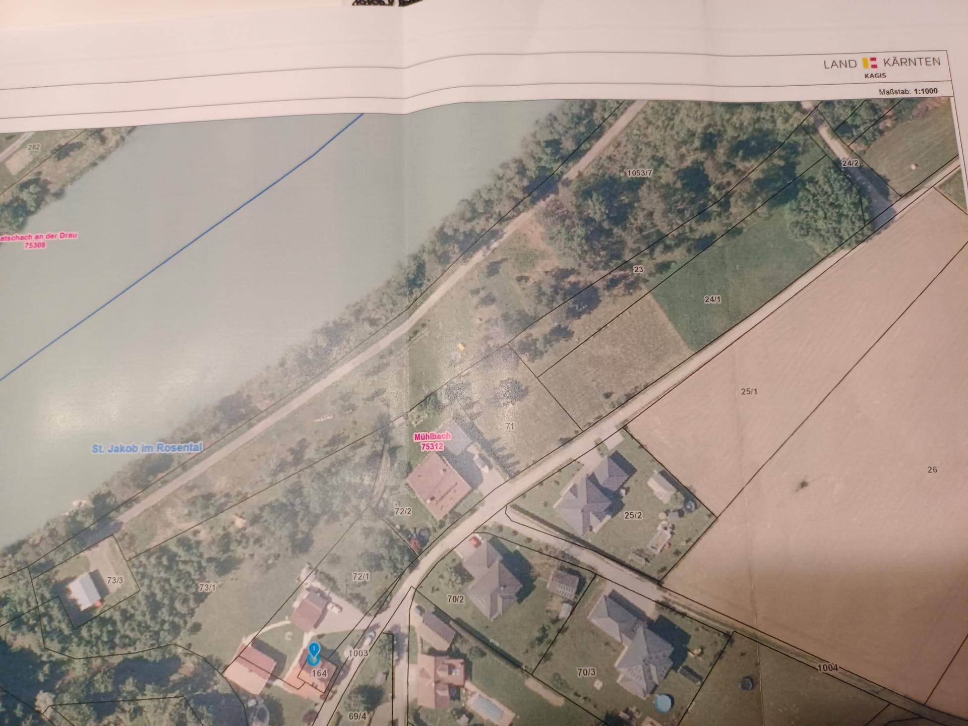 Katasterplan von Kärnten mit Grundstücksgrenzen, Flussverlauf und umliegenden Gebäuden im Maßstab 1:1000.