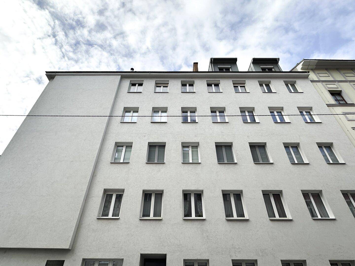 Moderne Fassade eines Mehrfamilienhauses mit zahlreichen Fenstern und klarem Design.