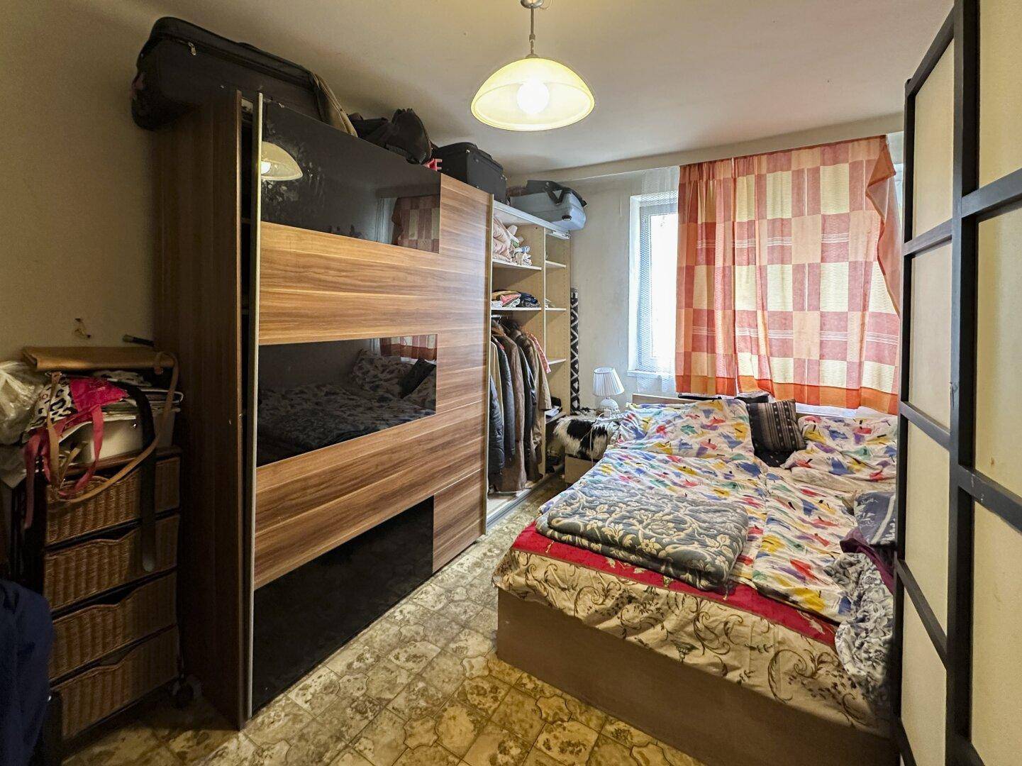 Schlafzimmer mit Bett, großem Kleiderschrank und Fenster, das natürliches Licht hereinlässt.