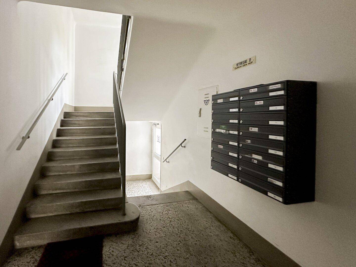 Helles Treppenhaus mit Briefkästen und klaren Linien, führt zu den oberen Etagen.