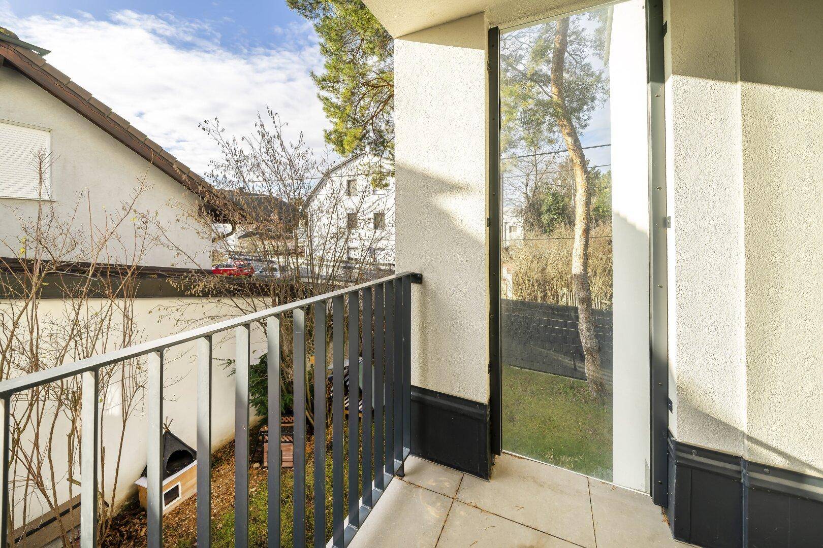 Balkon mit Fliesenboden und Metallgeländer, bietet Blick auf den Garten und die Umgebung.