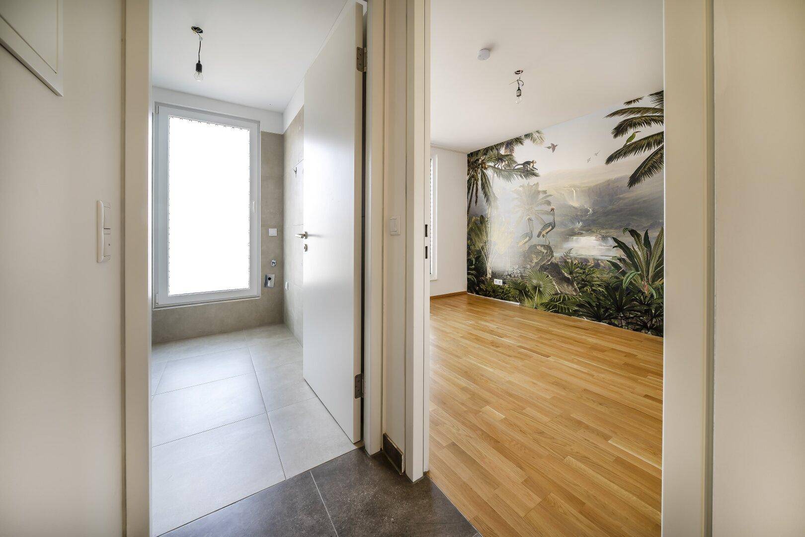 Flur mit Fliesenboden, der zu einem Badezimmer und einem weiteren Zimmer führt.