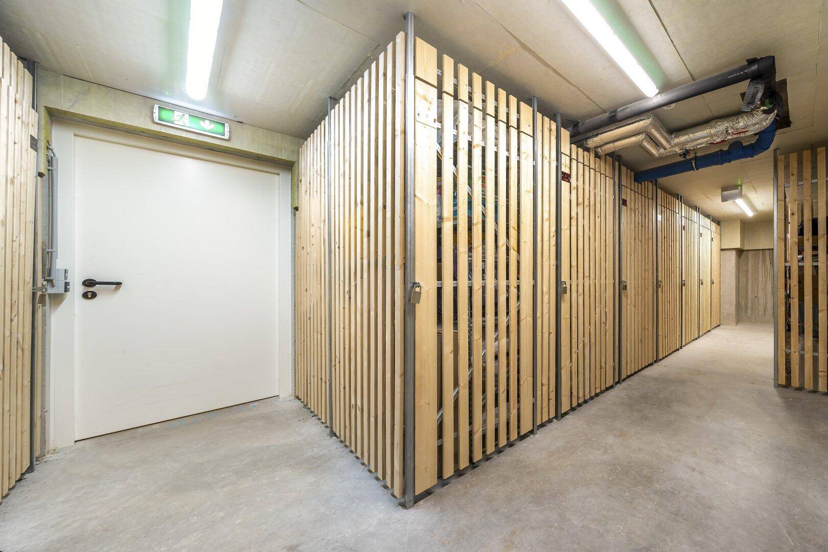 Kellerabteil mit individuellen Lagereinheiten aus Holzlatten und Betonboden.