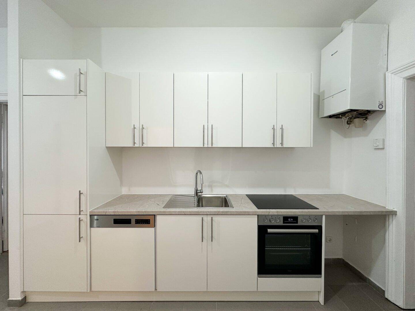 Moderne Einbauküche mit weißen Schränken, Induktionskochfeld und integriertem Geschirrspüler.