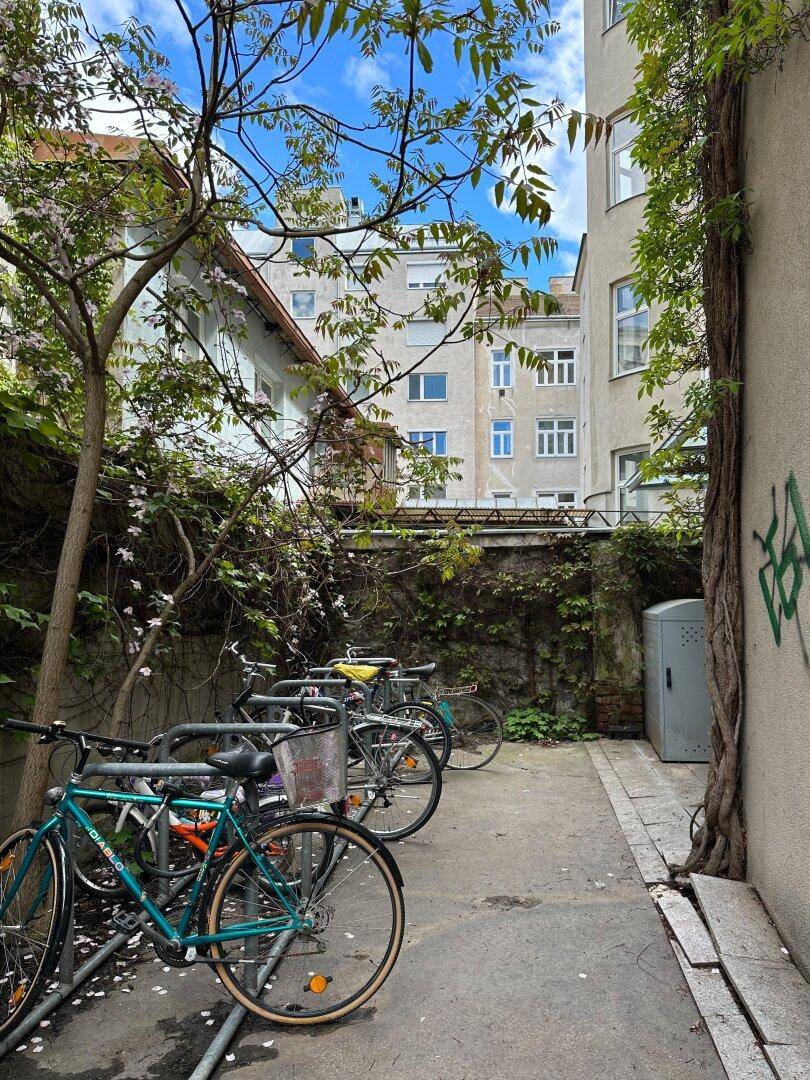 Fahrradstellplätze in einem begrünten Innenhof mit Gebäuden im Hintergrund.