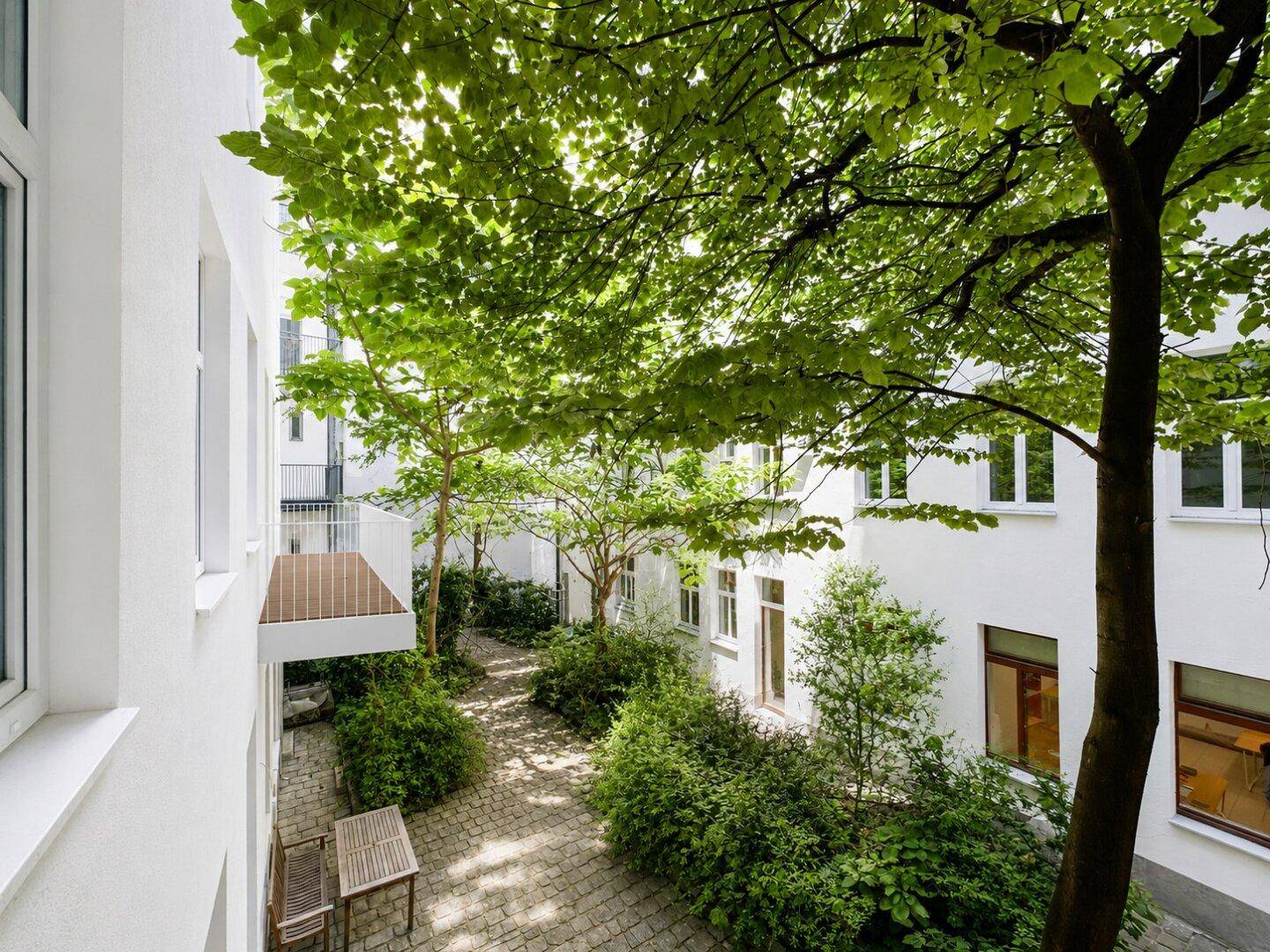 Vogelperspektive auf einen begrünten Innenhof mit Bäumen und Sitzgelegenheiten zwischen den Gebäuden.