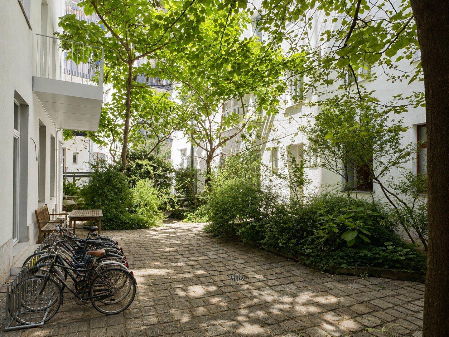 Grüner Innenhof mit Fahrradständern und Sitzgelegenheiten, umgeben von Gebäuden.
