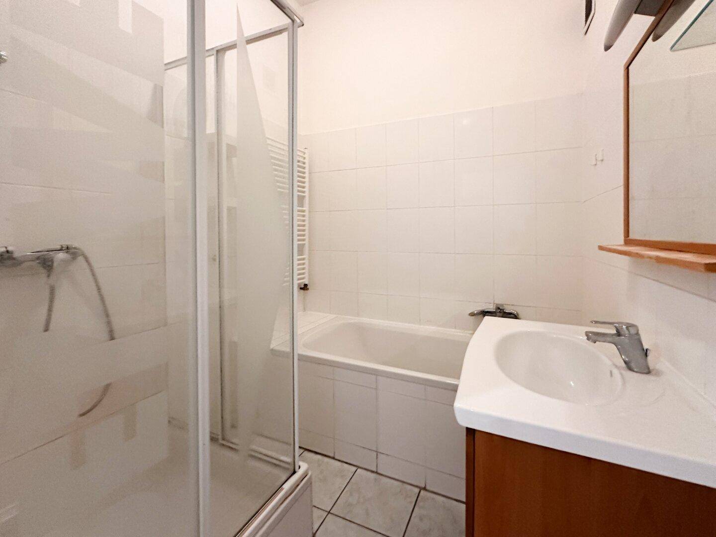 Badezimmer mit Duschkabine, Badewanne, Waschbecken und beheiztem Handtuchhalter.