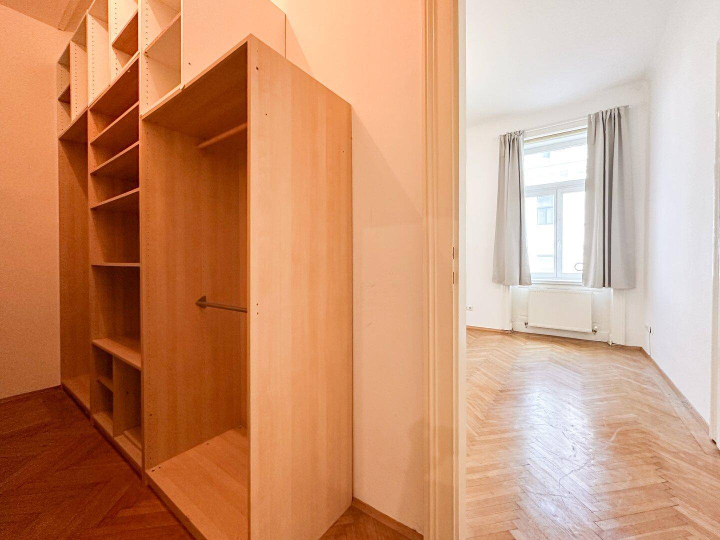 Praktischer Einbauschrank mit Regalen und Kleiderstange, angrenzend an ein helles Zimmer.