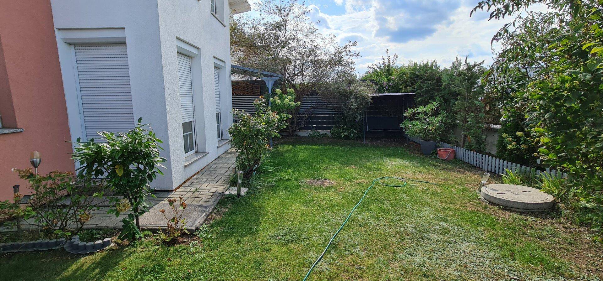 Gepflegter Garten mit Rasenfläche, Bäumen und Sträuchern, ideal zum Entspannen.