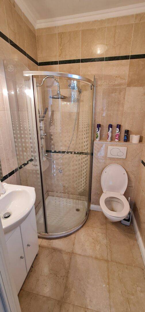 Modernes Badezimmer mit Duschkabine, WC, Fliesenboden und Waschbecken.