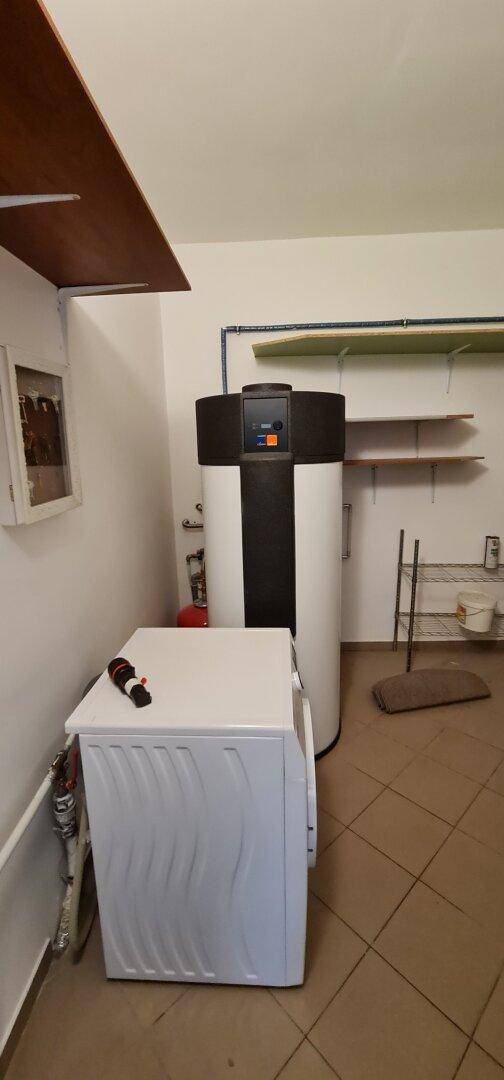 Hauswirtschaftsraum mit Waschmaschine, Warmwasserspeicher und praktischen Regalen.