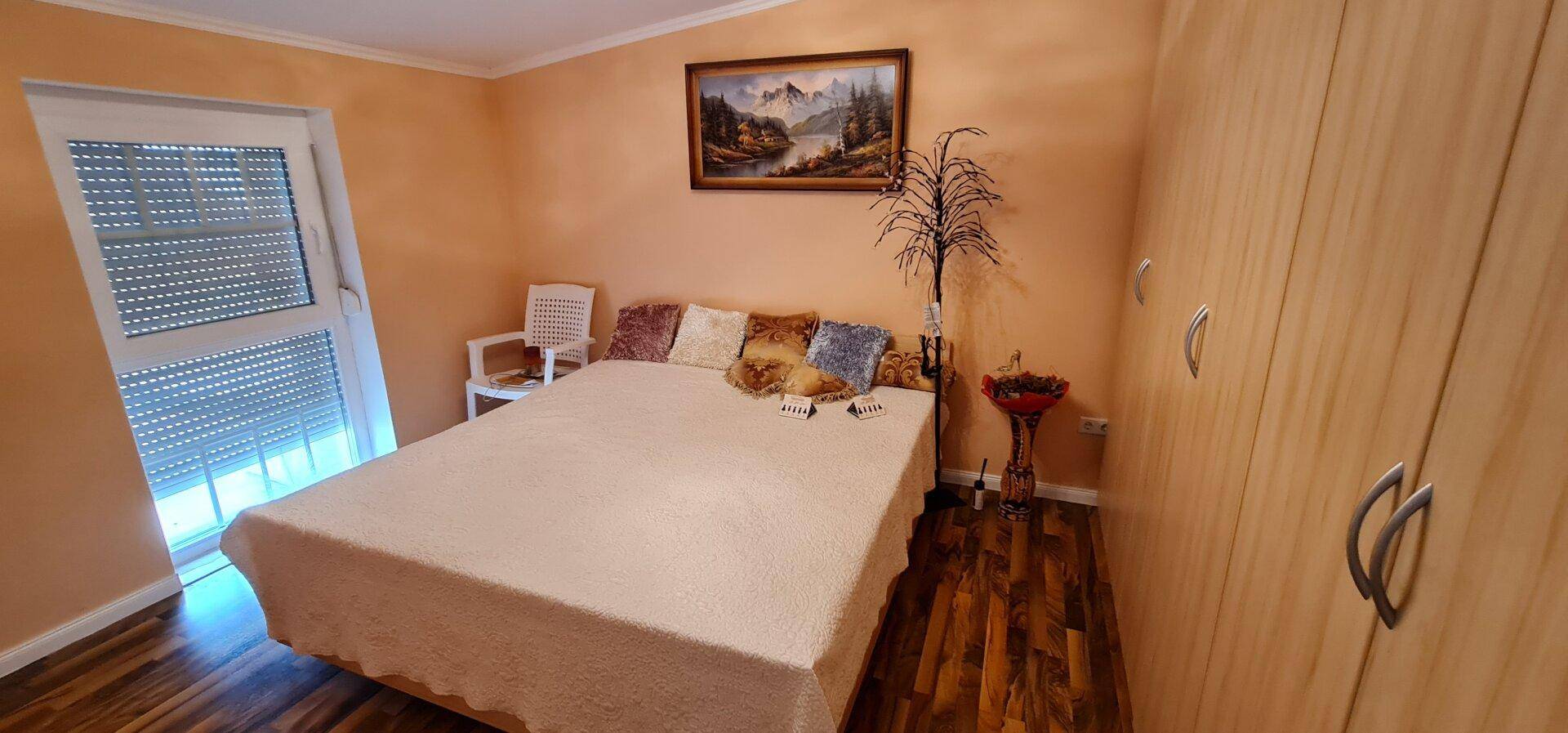 Helles Schlafzimmer mit Holzboden, großem Fenster und Kleiderschrank für Komfort.