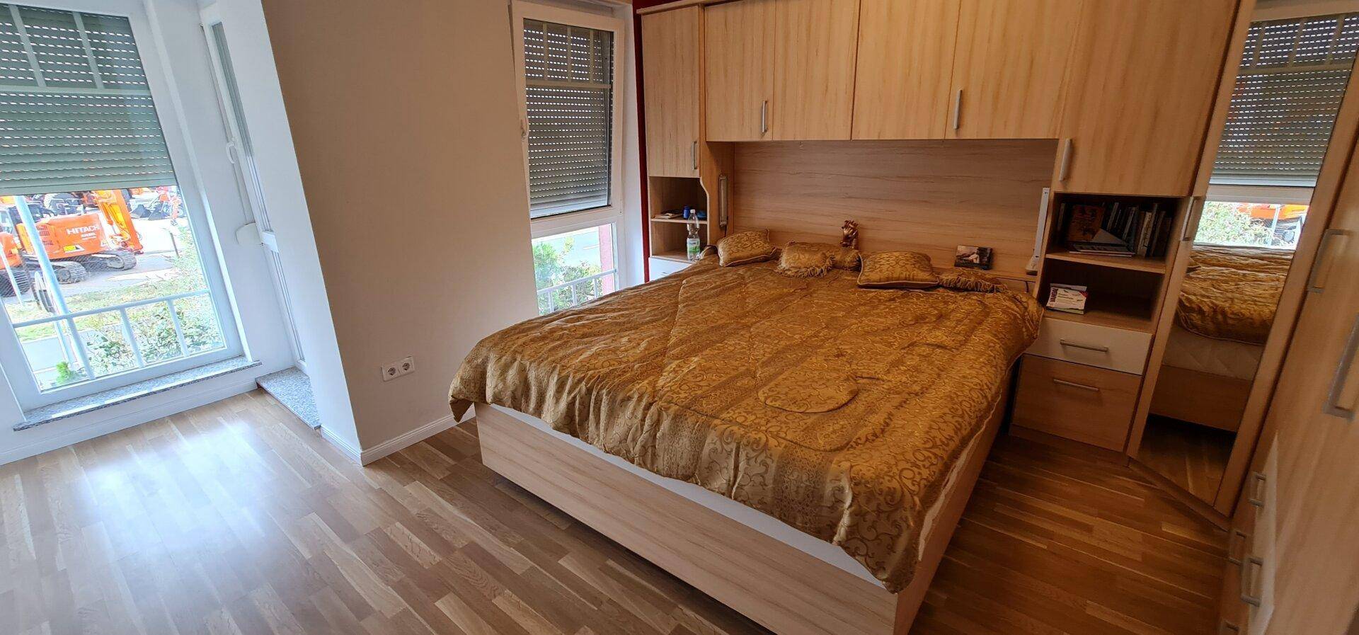 Schlafzimmer mit Einbauschränken, Holzboden und großem Fenster für viel Tageslicht.